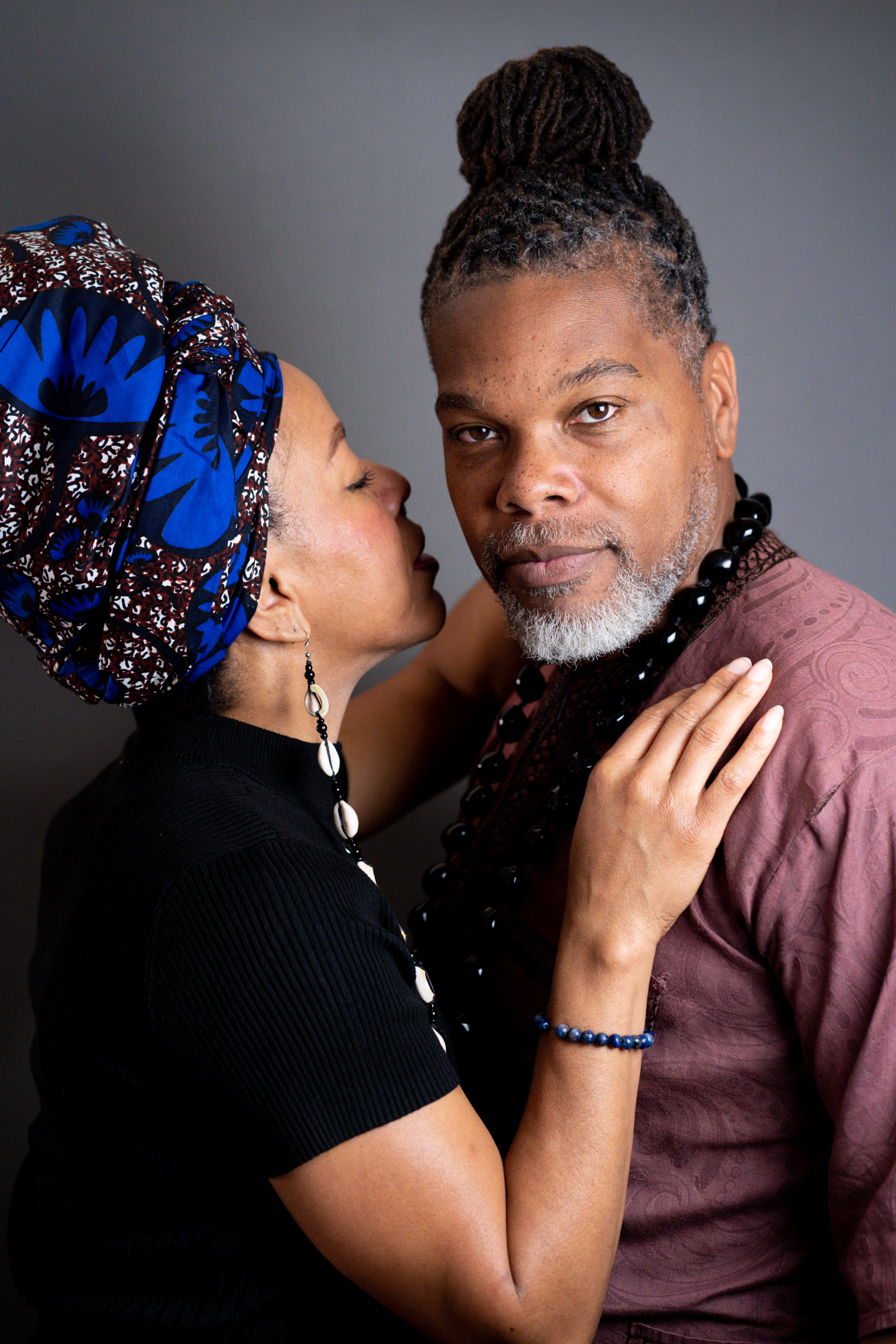 Couple portrait, woman in blue head wrap leaning toward man with locs
